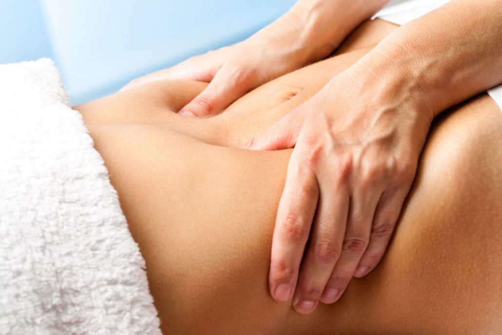 Manos de terapeuta realizando drenaje de colon