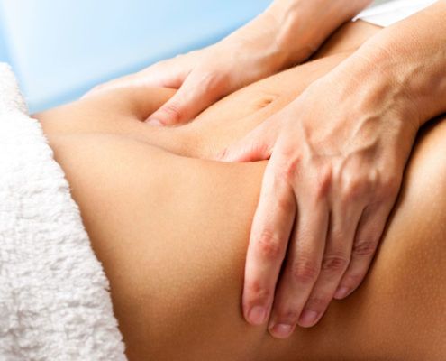 Manos de terapeuta realizando drenaje de colon